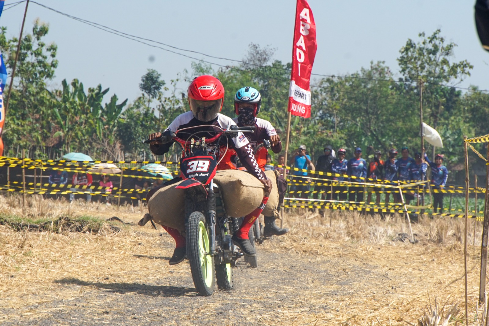 Peserta menggeber motor trail sambil membawa gabah di lintasan sawah Desa Mangunharjo, Ngawi, kemarin. FOTO: MUSTOFA FAHMI UNTUK JAWA POS RADAR NGAWI