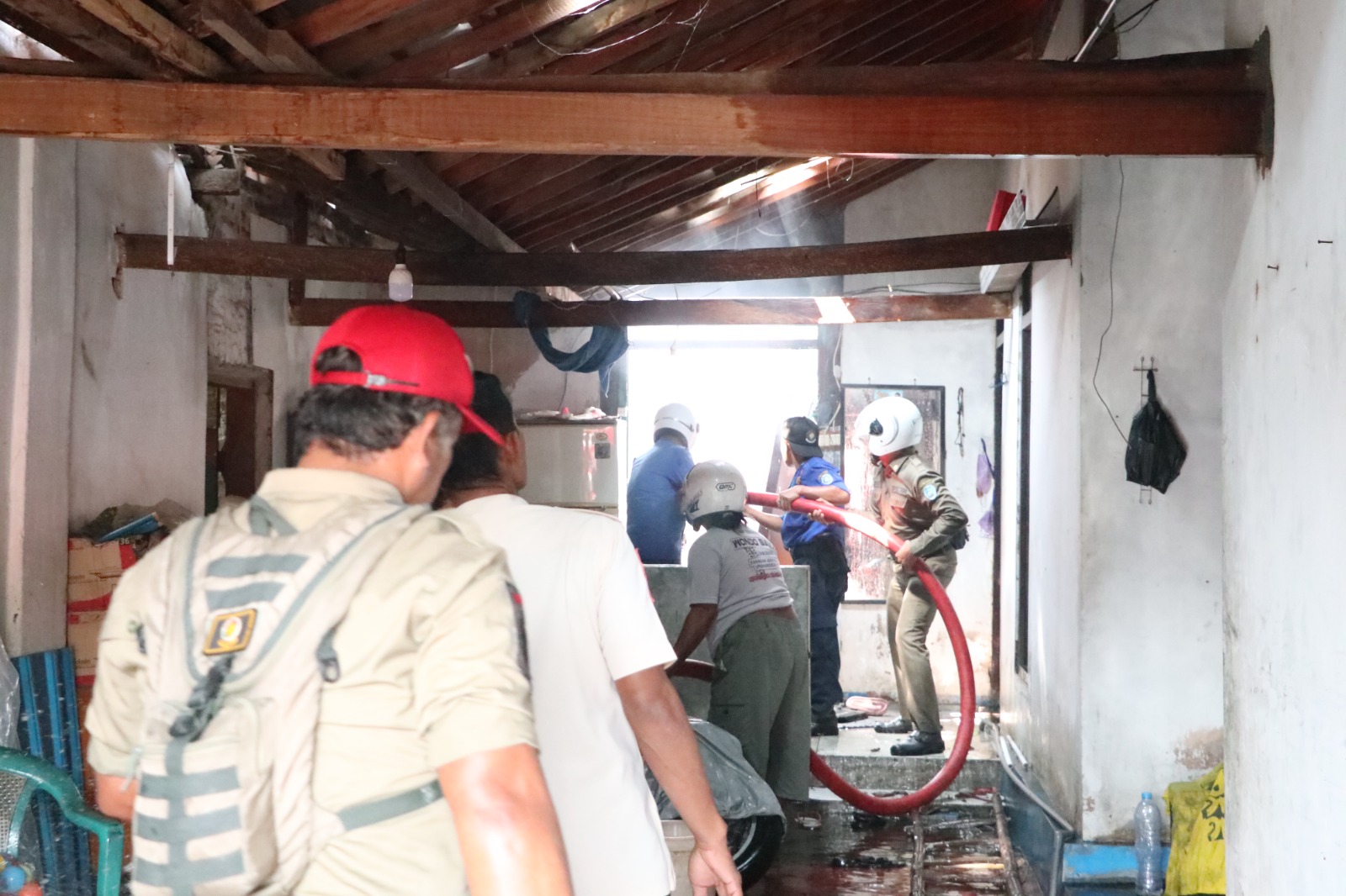 Petugas damkar menjinakkan api yang membakar rumah warga di Jalan Jola-Joli, Tambak Bayan, Ponorogo, Kamis (24/7) pagi. FOTO: SUGENG DWI N/RADAR PONOROGO