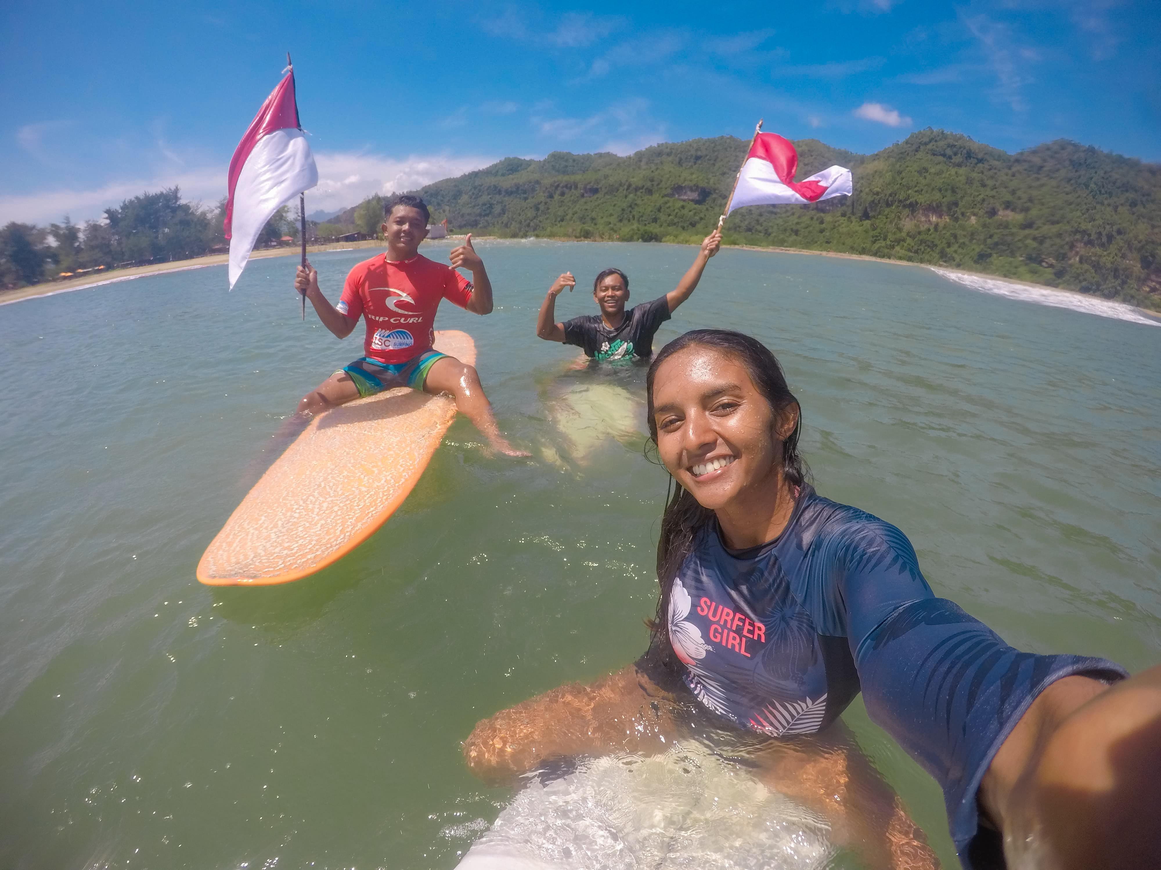 Surfer Pacitan Salini Rengganis mengibarkan bendera Merah Putih saat berselancar di Pantai Pancer Dorr, Minggu (17/8). FOTO: SALINI RENGGANIS