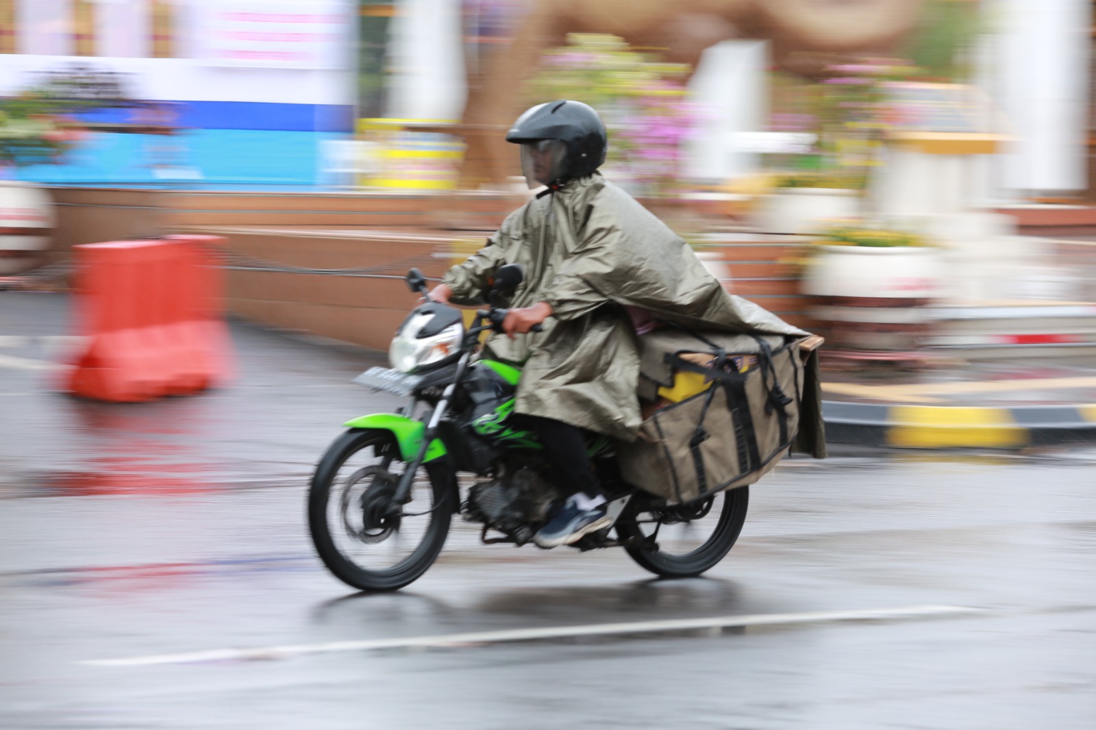Seorang pemotor berkendara saat hujan.