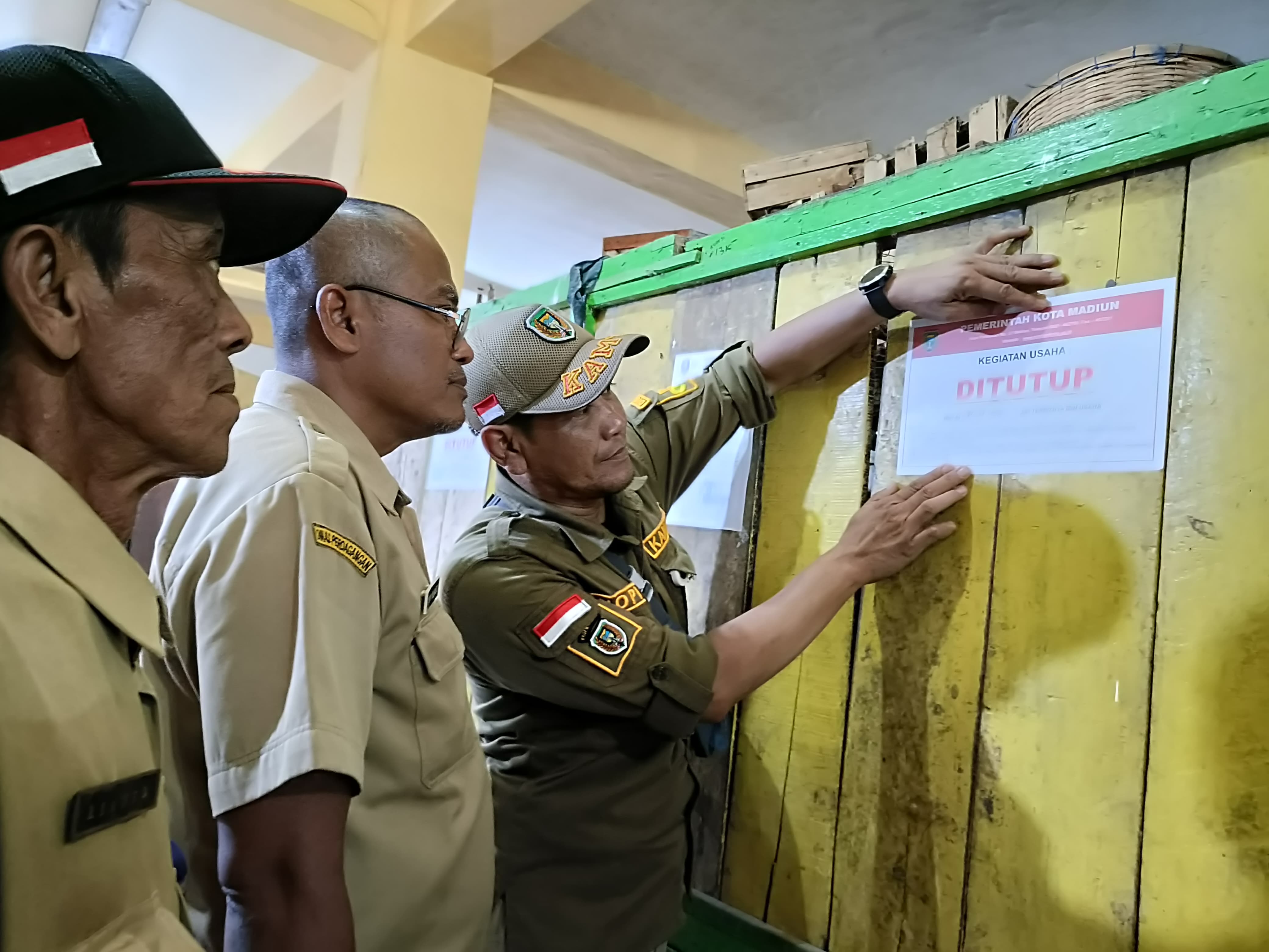 Petugas Dinas Perdagangan Kota Madiun menempel stiker segel pada salah satu kios Pasar Sleko, buntut praktik sewa ilegal. HENGKY RISTANTO/RADAR MADIUN