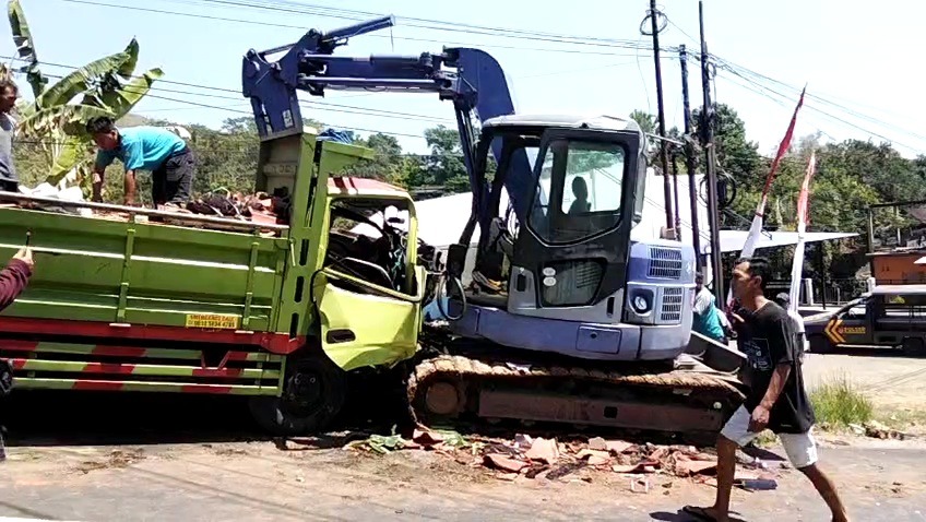 Polisi mengamankan truk dan eskavator yang terlibat kecelakaan di Jalan Raya Kendal, Ngawi. Sopir truk kritis setelah terjepit kabin. FOTO: ISTIMEWA
