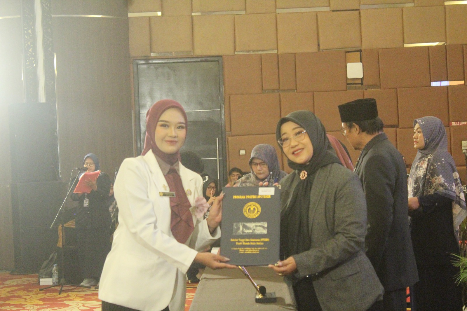 Ketua Stikes BHM Madiun Retno Widiarini menyerahkan ijazah apoteker kepada wisudawan dalam prosesi sumpah di Aston Hotel, Sabtu (27/9). ARCHI FIRDAUS/RADAR MADIUN