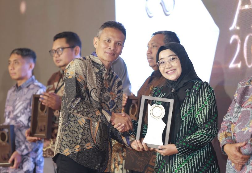 Ketua Stikes BHM Madiun Retno Widiarini menerima penghargaan Outstanding University dari Direktur Jawa Pos Radar Madiun Marsudi Nurwahid.