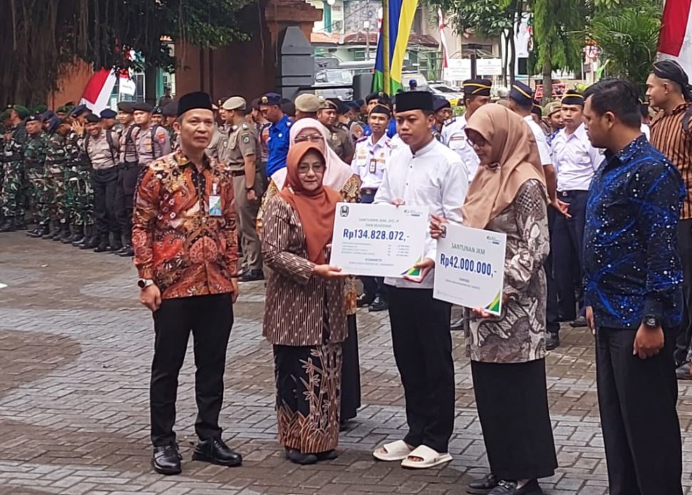 Bupati Magetan Nanik Endang Rusminiarti menyerahkan santunan dari BPJS Ketenagakerjaan.