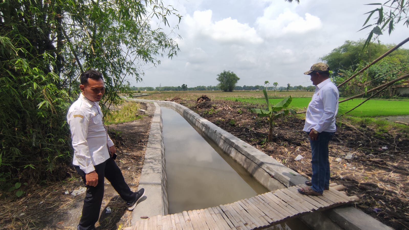 CEK SALURAN AIR: Kepala Desa Waruk Kalong tengah memastikan bangunan saluran air dari kegiatan pembangunan fisik terbaru tahun 2025 ini berfungsi optimal.