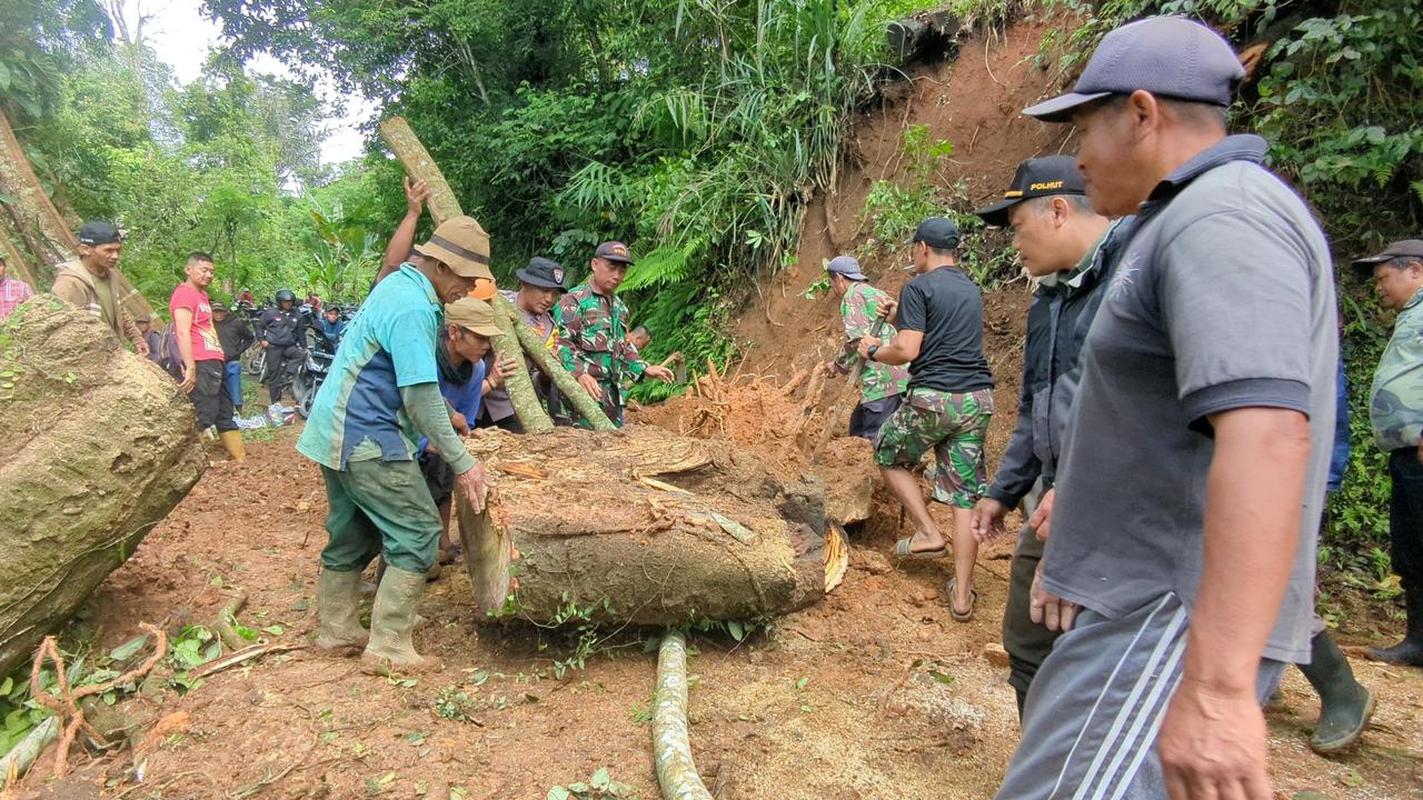Warga bersama anggota TNI/Polri membersihkan pohon besar yang tumbang dan menutup akses Jalan Madiun&ndash;Ponorogo di Dusun Kandangan, Kare. DIAN RAHAYU/RADAR MADIUN