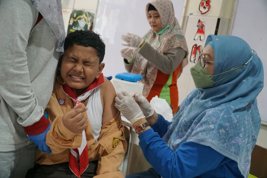 Petugas kesehatan menyuntikkan vaksin TD kepada siswa SD Al Irsyad dalam program BIAS yang digelar Puskesmas Ngegong. FOTO: DISKOMINFO KOTA MADIUN