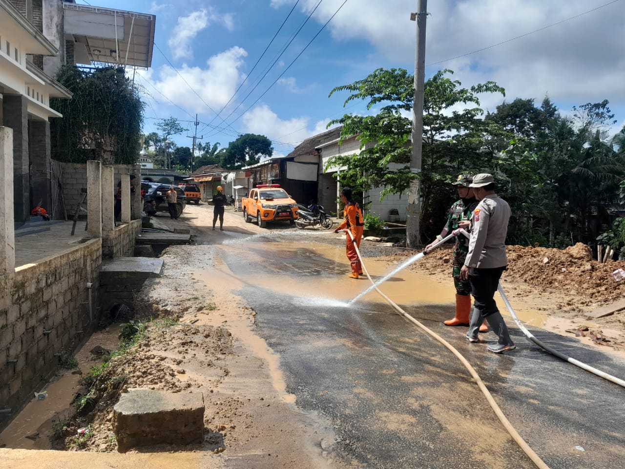 Petugas BPBD Ponorogo menyemprot jalan Wagir Kidul untuk menghilangkan sisa material longsor setelah akses desa kembali dibuka. BPBD UNTUK JAWA POS RADAR PONOROGO