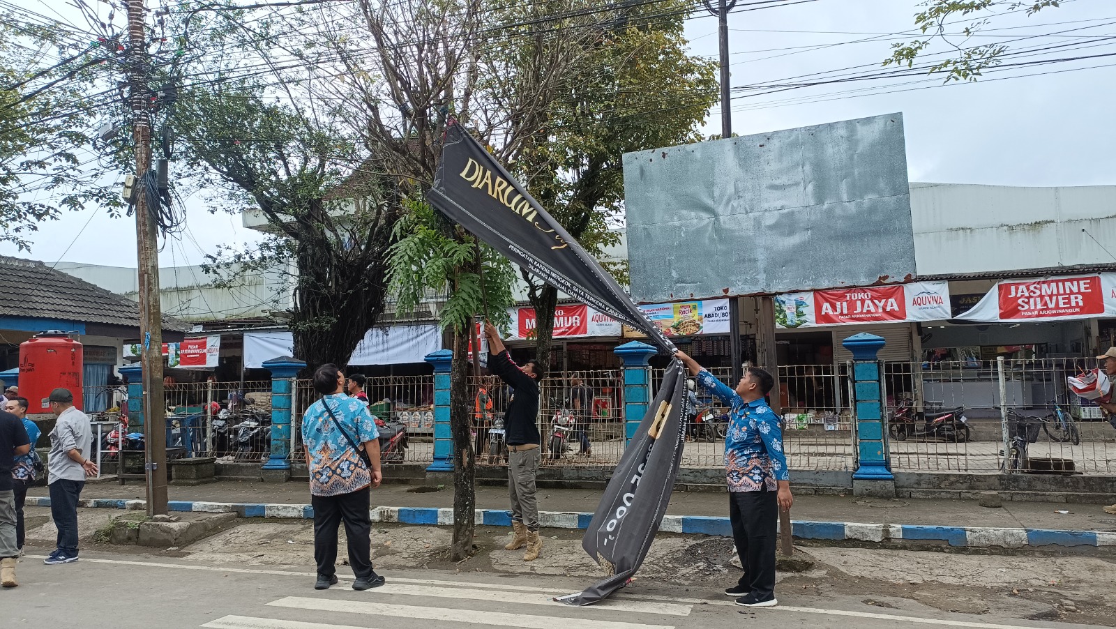 Petugas Satpol PP Pacitan menurunkan spanduk dan baliho tak berizin di depan Pasar Arjowinangun yang dinilai mengganggu estetika kota. NUR CAHYONO/RADAR PACITAN
