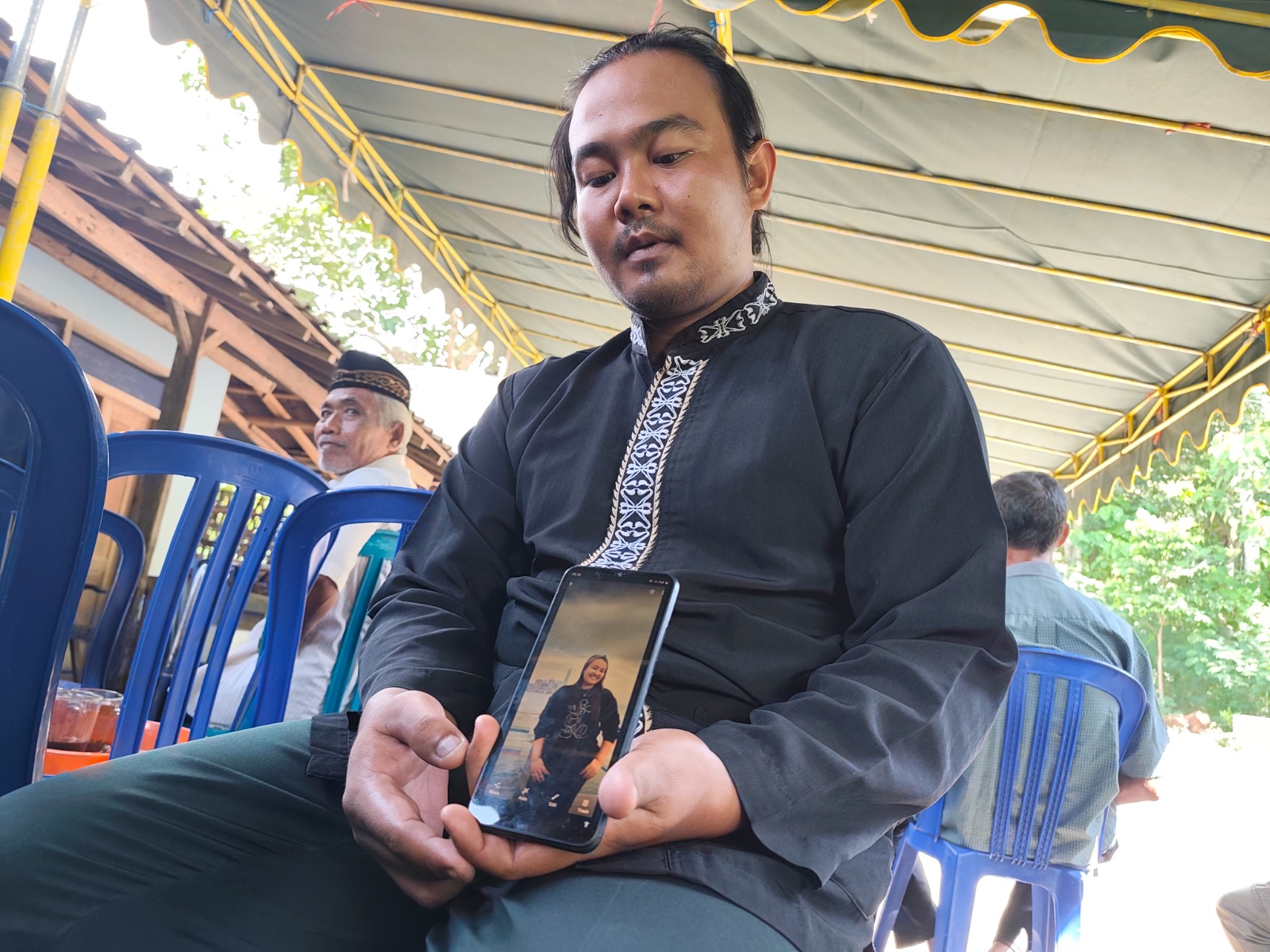 Riko Andi, adik Dina Martiana, menunjukkan foto terakhir mendiang kakaknya yang menjadi korban kebakaran apartemen Wang Fuk Court, Hongkong. SUGENG DWI N./JAWA POS RADAR PONOROGO