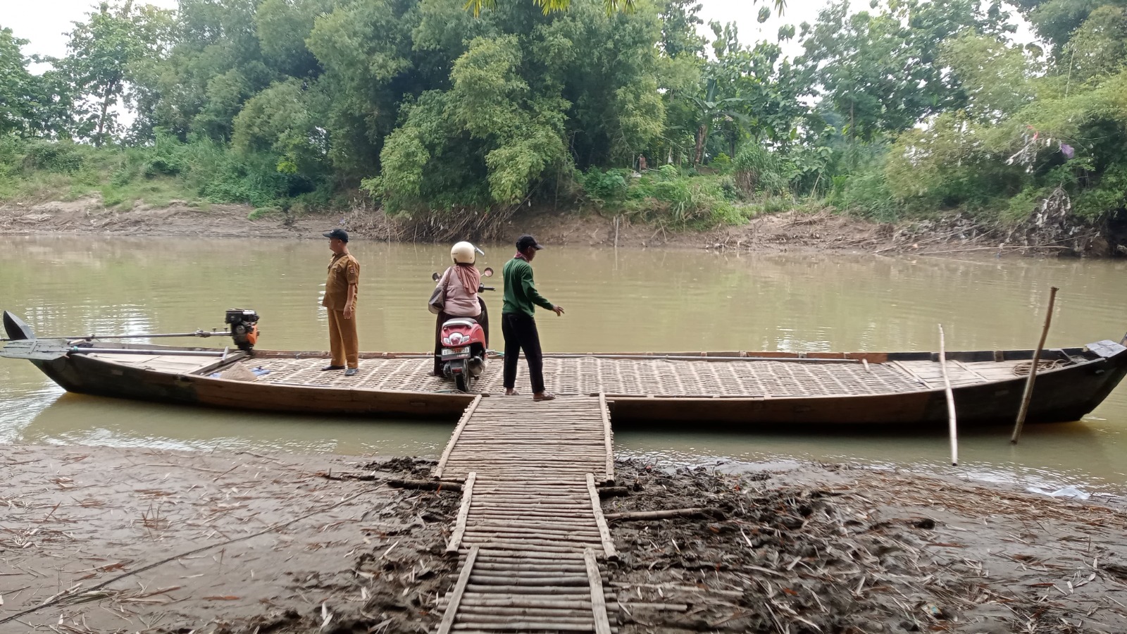 Warga Desa Ngompro, Pangkur, menyeberang Bengawan Madiun menggunakan perahu getek, akses vital menuju Kwadungan yang tetap beroperasi meski penuh risiko. ULUL RUBIYATUN/MAGANG/JAWA POS RADAR NGAWI