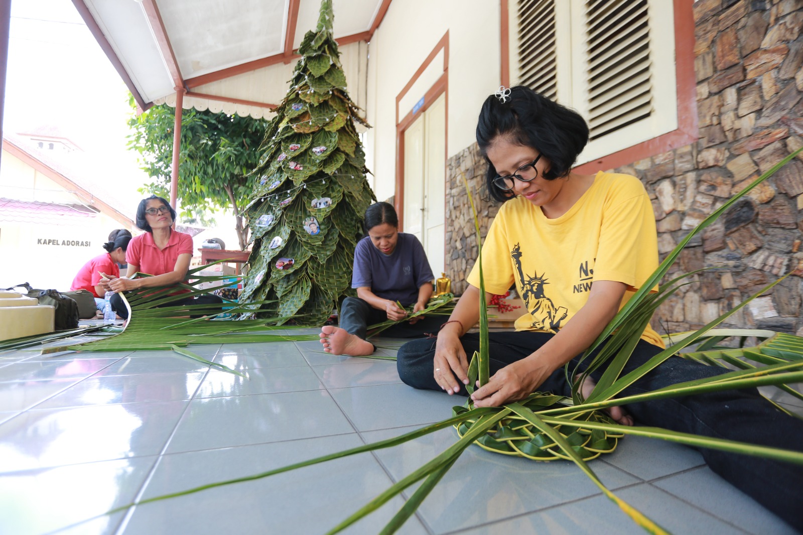 Ibu-ibu Paroki Santo Cornelius Madiun menyusun pohon Natal setinggi dua meter dari anyaman blarak sebagai dekorasi utama perayaan Natal 2025. BAGAS BIMANTARA/JAWA POS RADAR MADIUN