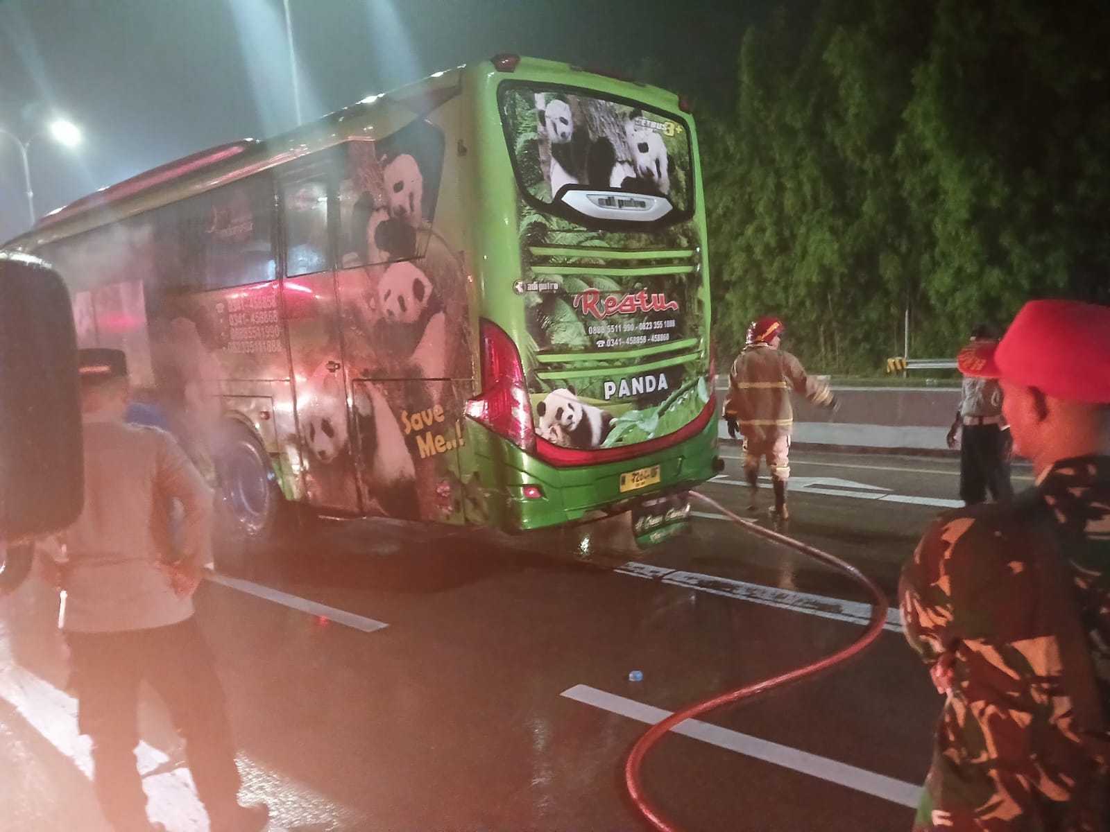 Petugas Damkar Kabupaten Madiun memadamkan api yang hampir melalap bus antarkota di Exit Tol Dumpil, Desa Tiron, Minggu (21/12) malam. FOTO: ISTIMEWA
