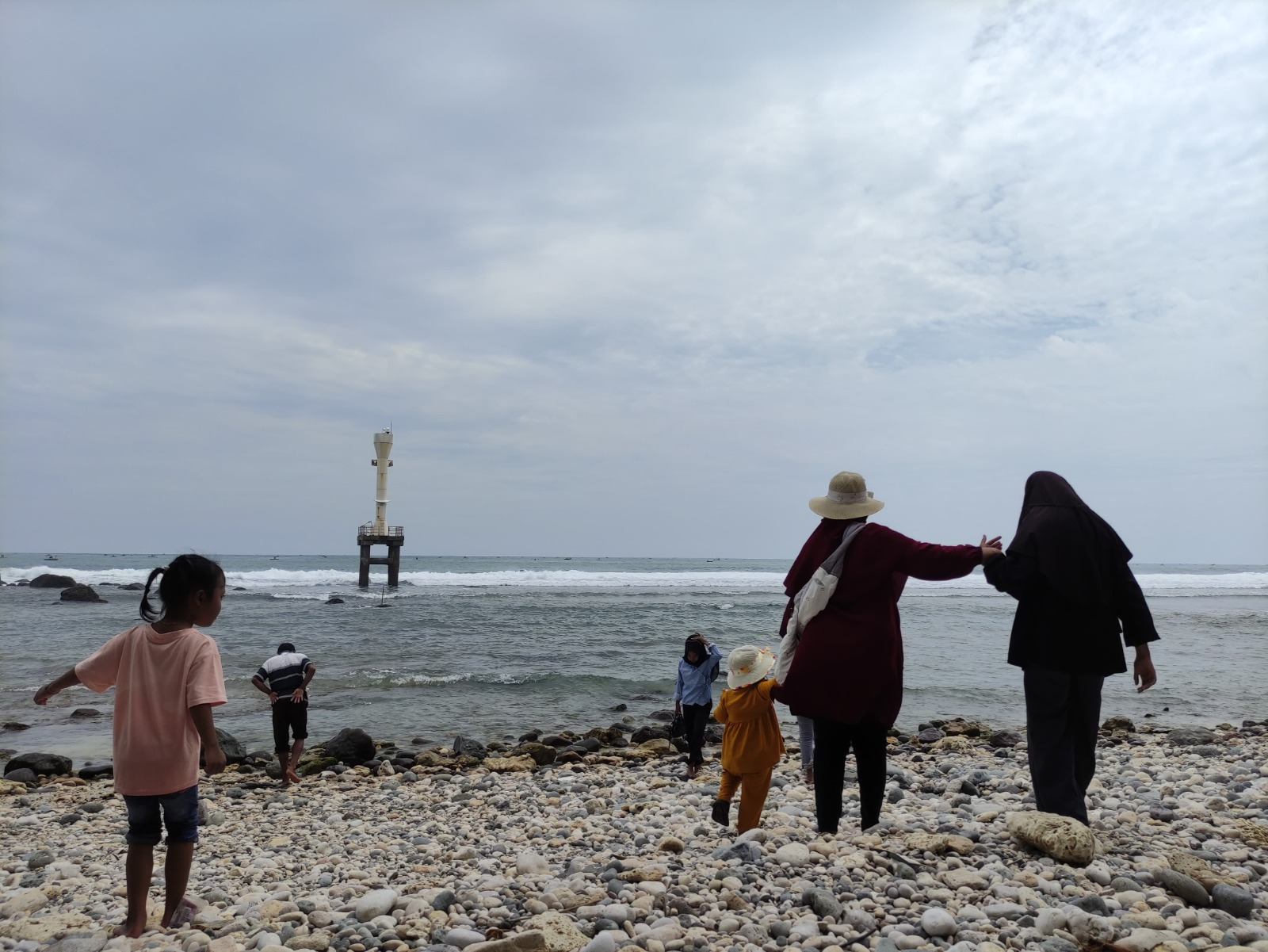 INDAH: Wisatawan menikmati panorama Pantai Pidakan dengan hamparan kerikil putih yang menjadi ciri khas destinasi di Desa Jetak, Tulakan, Pacitan. NUR CAHYONO/RADAR PACITAN