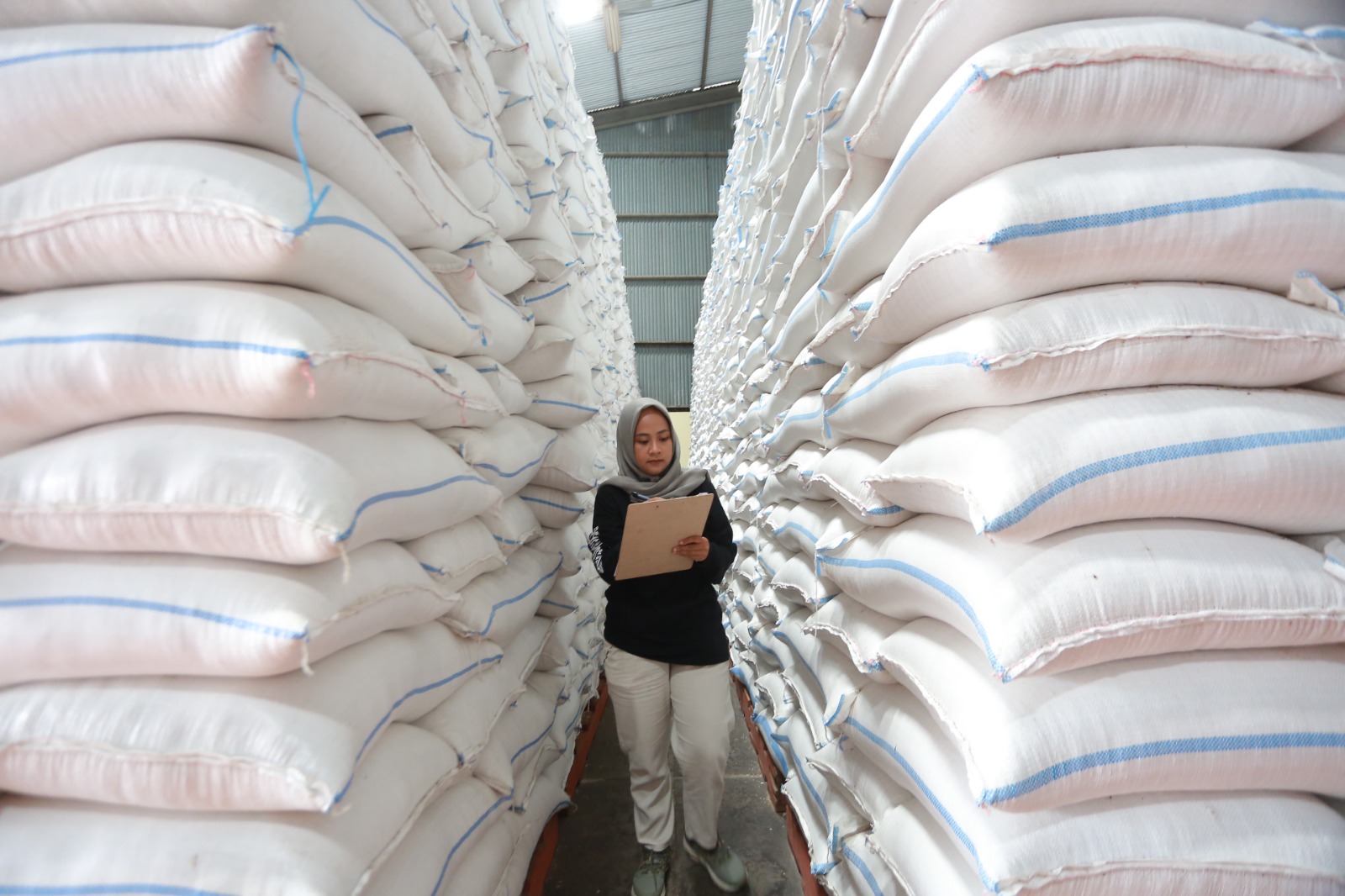 MENUMPUK: Petugas Perum Bulog Cabang Madiun memantau stok beras yang ada di gudang Kelurahan Nambangan Lor, Kecamatan Manguharjo. BAGAS BIMANTARA/JAWA POS RADAR MADIUN