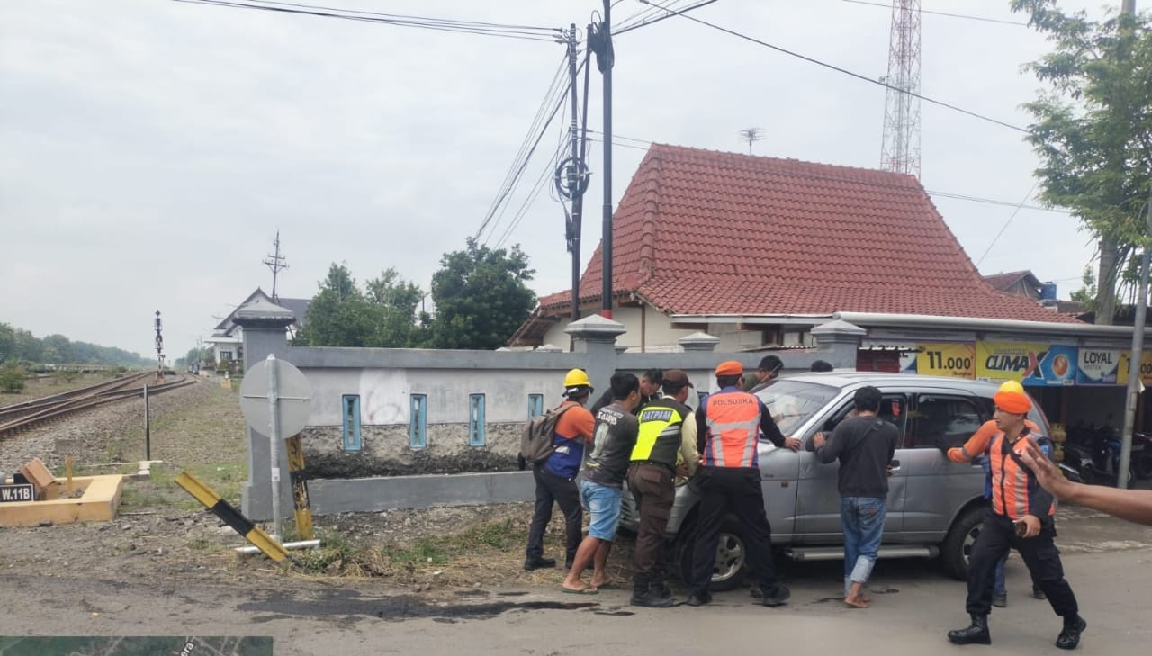 RINGSEK: Petugas mengevakuasi mobil Daihatsu Taruna yang terguling setelah menabrak palang pintu perlintasan kereta api di Kedunggalar, Ngawi. FOTO: ISTIMEWA