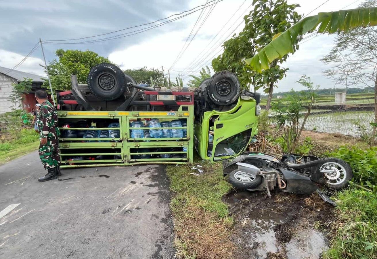 TERBALIK: Truk pengangkut galon terbalik di Jalan Ngawi&ndash;Kedunggalar usai menabrak sepeda motor pelajar, Rabu (21/1). FOTO: ISTIMEWA