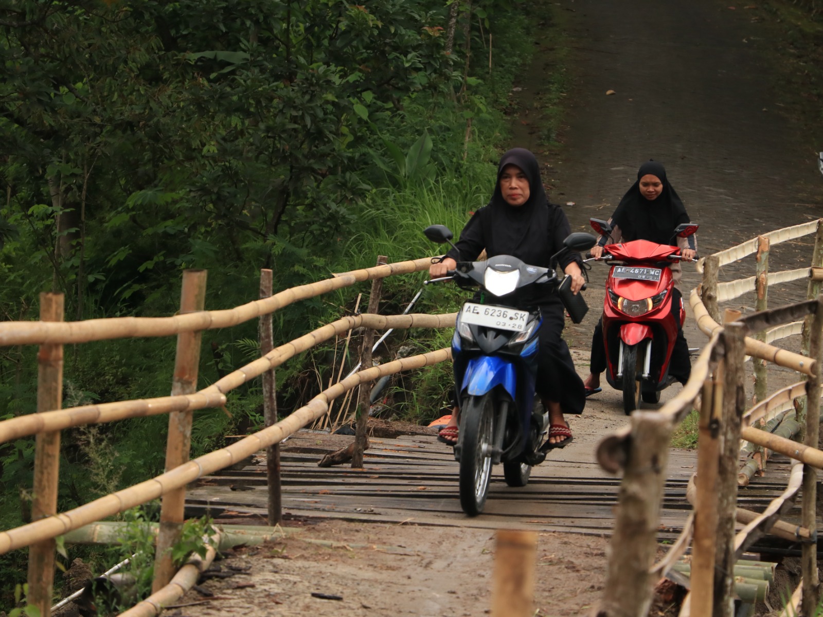 Warga Desa Wagir Lor, Kecamatan Ngebel, membangun jembatan darurat dari bambu di atas jalan amblas akibat longsor, dengan lebar jalan tersisa sekitar setengah meter. SUGENG DWI N/RADAR PONOROGO