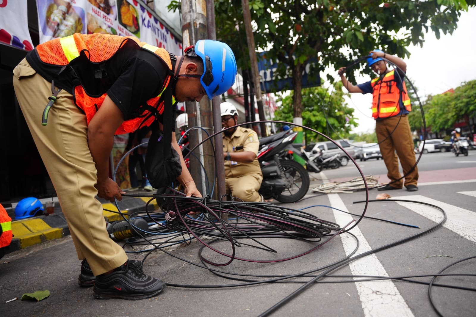 DIPUTUS: Petugas Diskominfo Kota Madiun menertibkan kabel fiber optik udara yang melintang di Jalan Panglima Sudirman sebagai bagian penataan utilitas kota kemarin (27/1
