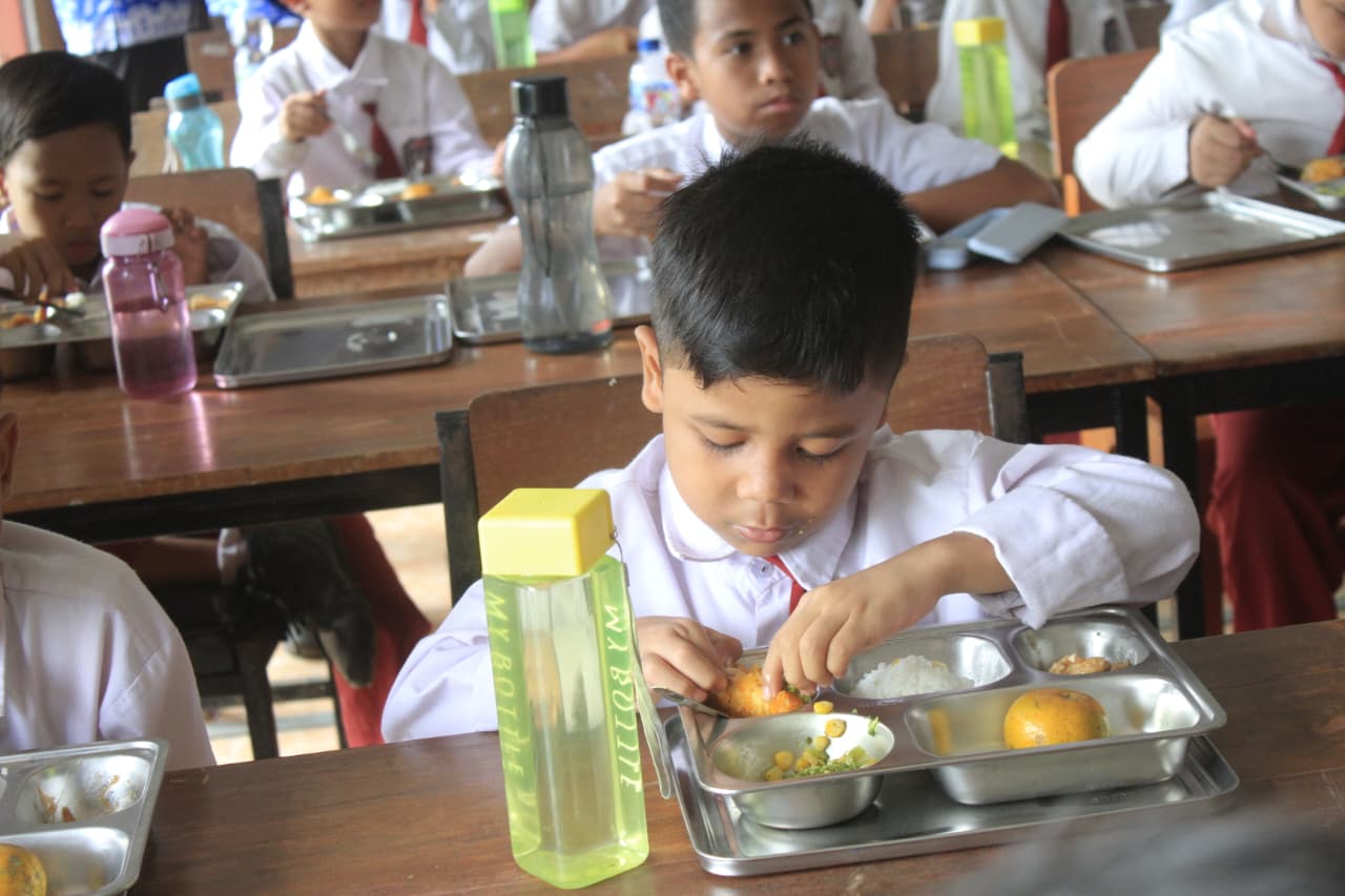 Anak-anak menikmati menu Makan Bergizi Gratis (MBG) dari SPPG pondok pesantren yang menggunakan beras premium Bulog. DOK RADAR MAGETAN