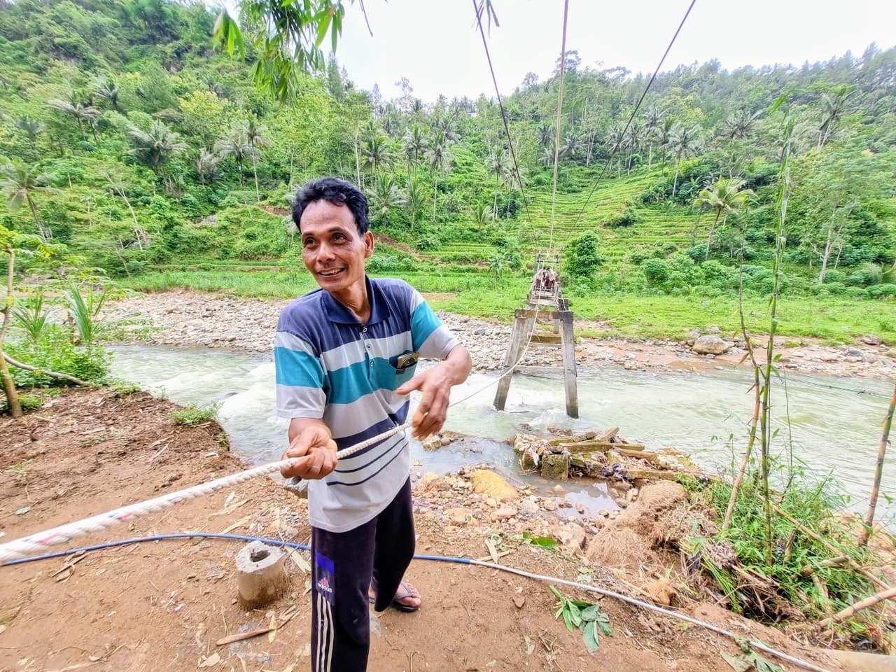 PAHLAWAN PERBATASAN: Lamidi bersama warga menarik gondola yang mengangkut tiga orang dan satu sepeda motor menyeberangi Sungai Jabak di Ngrayun. SUGENG DWI N/RADAR PONOROGO