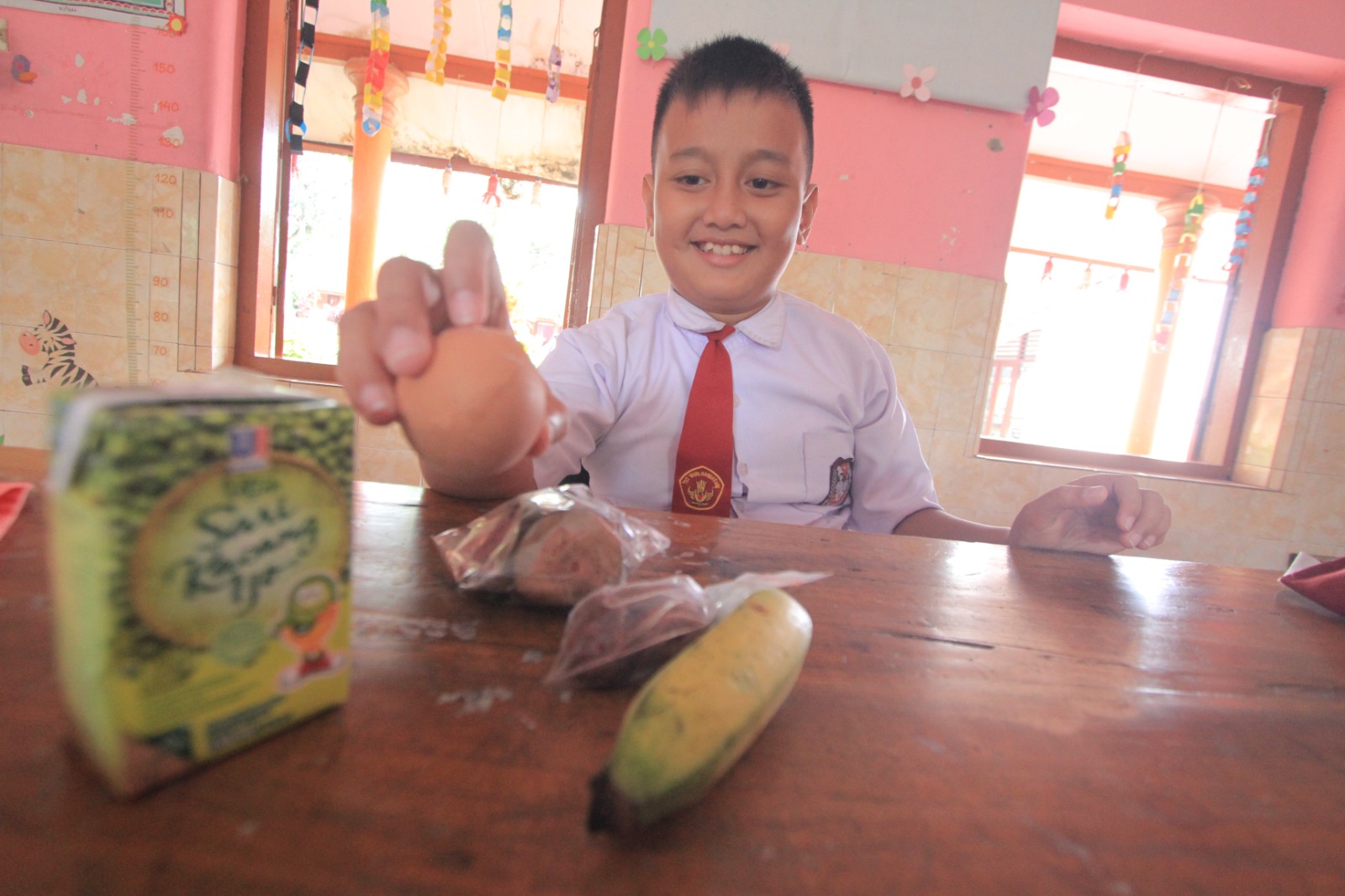 MBG RAMADAN: Siswa SD di Magetan menunjukkan paket Makan Bergizi Gratis berupa menu kering yang dibawa pulang untuk berbuka puasa selama Ramadan. AJI PUTRA/RADAR MAGETAN