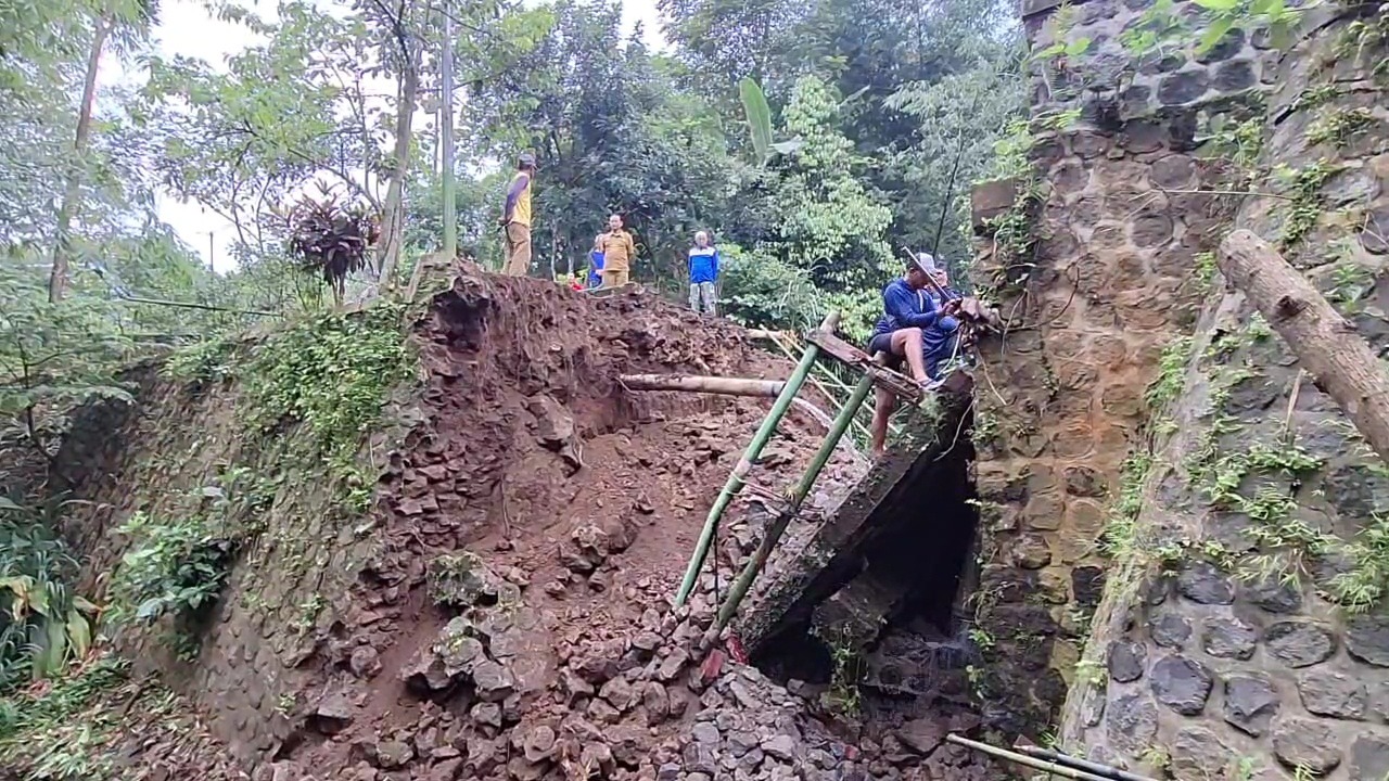 PUTUS TOTAL: Kondisi jembatan penghubung Desa Ngrambe dan Sidomulyo yang ambrol diterjang banjir, menghambat akses warga dan merusak pipa PDAM, Selasa (24/2). ASEP SYAEFUL/RADAR NGAWI
