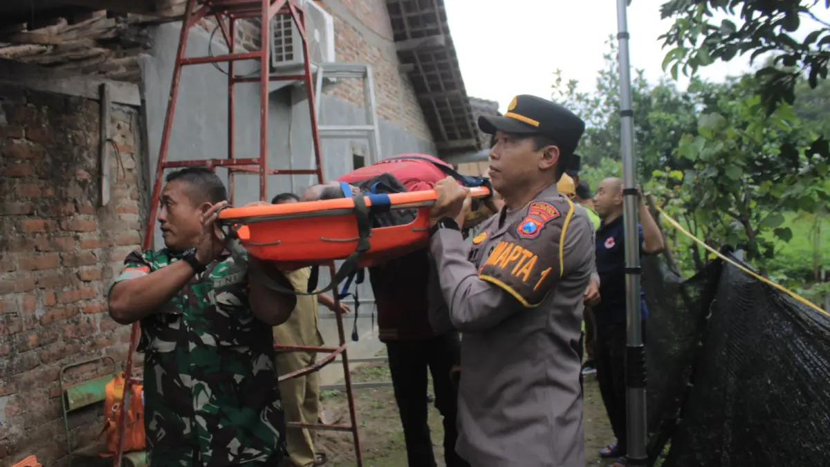 Petugas mengevakuasi jasad teknisi internet yang ditemukan meninggal di atas atap rumah warga di Sukomoro, Magetan. AJI PUTRA/RADAR MAGETAN
