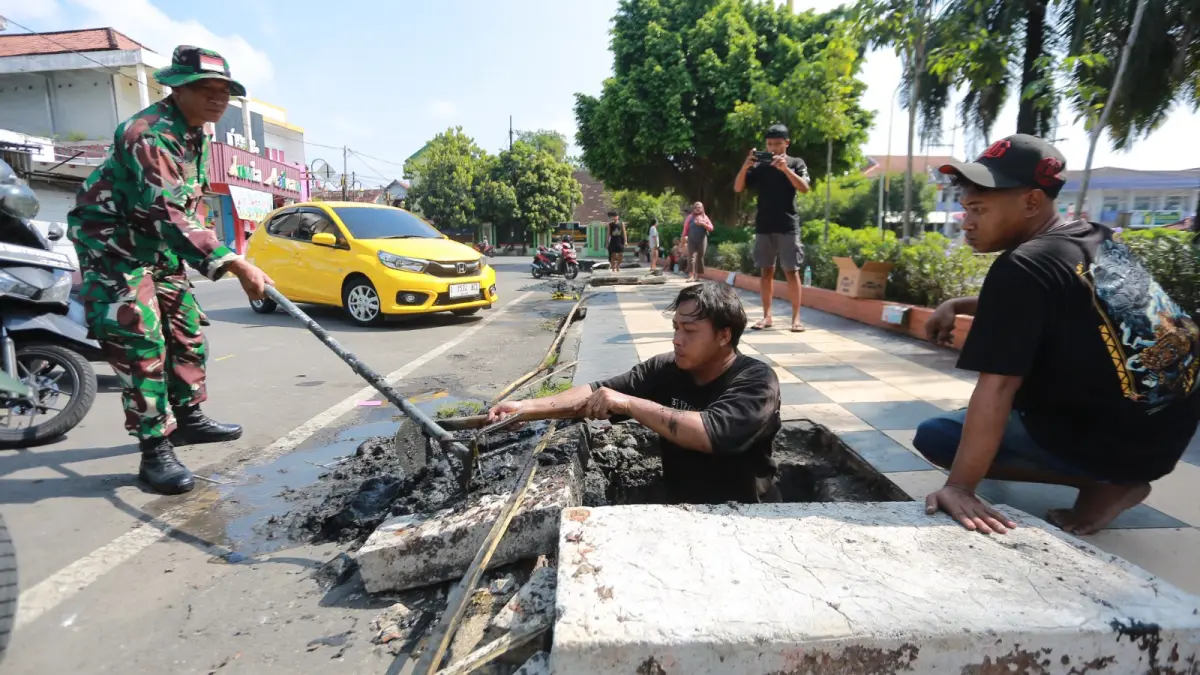 Petugas dari berbagai OPD membersihkan sampah yang menyumbat saluran drainase di kawasan Alun-Alun Kota Madiun. BAGAS BIMANTARA/RADAR MADIUN