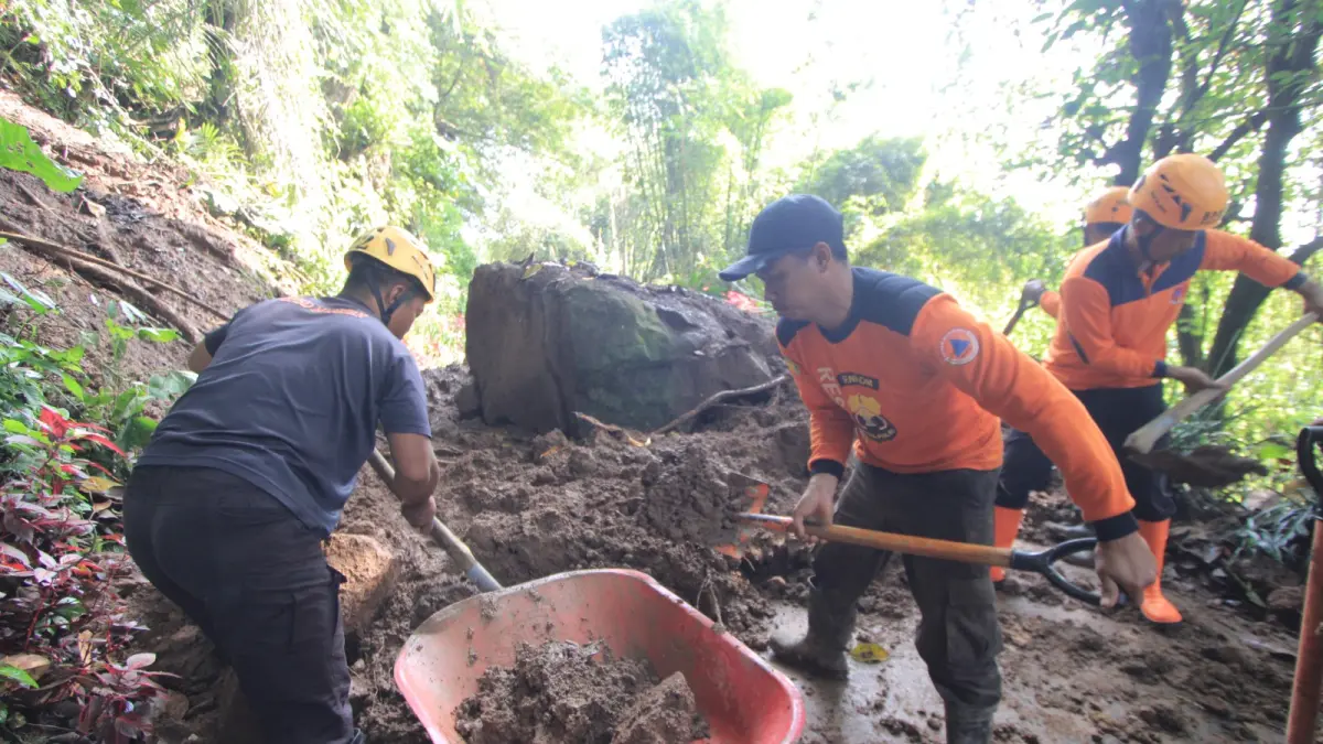 Petugas gabungan mengevakuasi material longsor yang menutup akses jalan di Desa Sidomulyo, Magetan. AJI PUTRA/RADAR MAGETAN