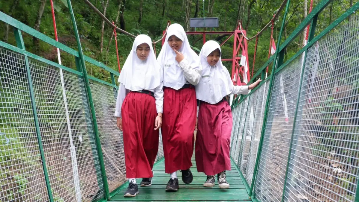 INFRASTRUKTUR: Warga melintasi jembatan gantung di Desa Gawang, Kecamatan Kebonagung, Pacitan, yang telah selesai dibangun dari program usulan infrastruktur. FOTO: ISTIMEWA