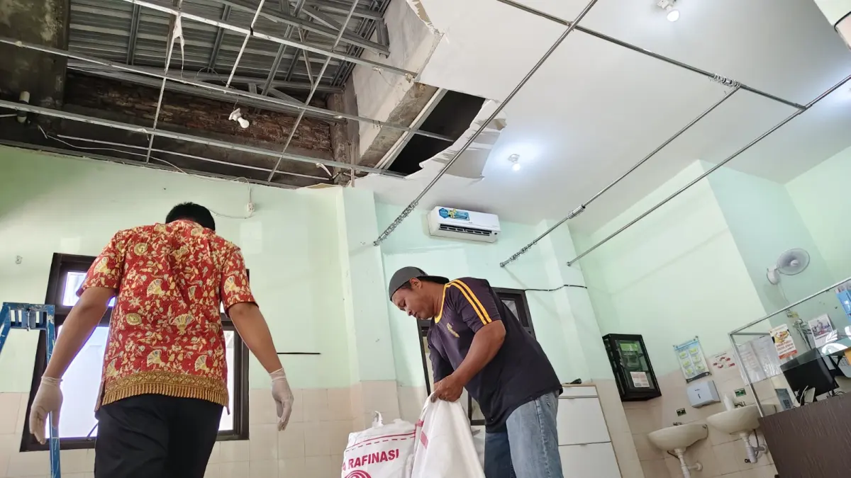 Petugas membersihkan material plafon UGD Puskesmas Slahung yang jebol akibat hujan deras. FOTO: PUSKESMAS SLAHUNG