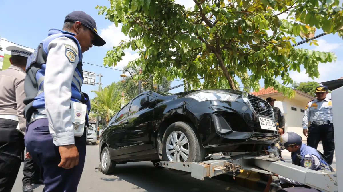 Petugas Dishub Kota Madiun menderek mobil pelanggar parkir di Jalan Dr Soetomo. FOTO: BAGAS BIMANTARA/RADAR MADIUN