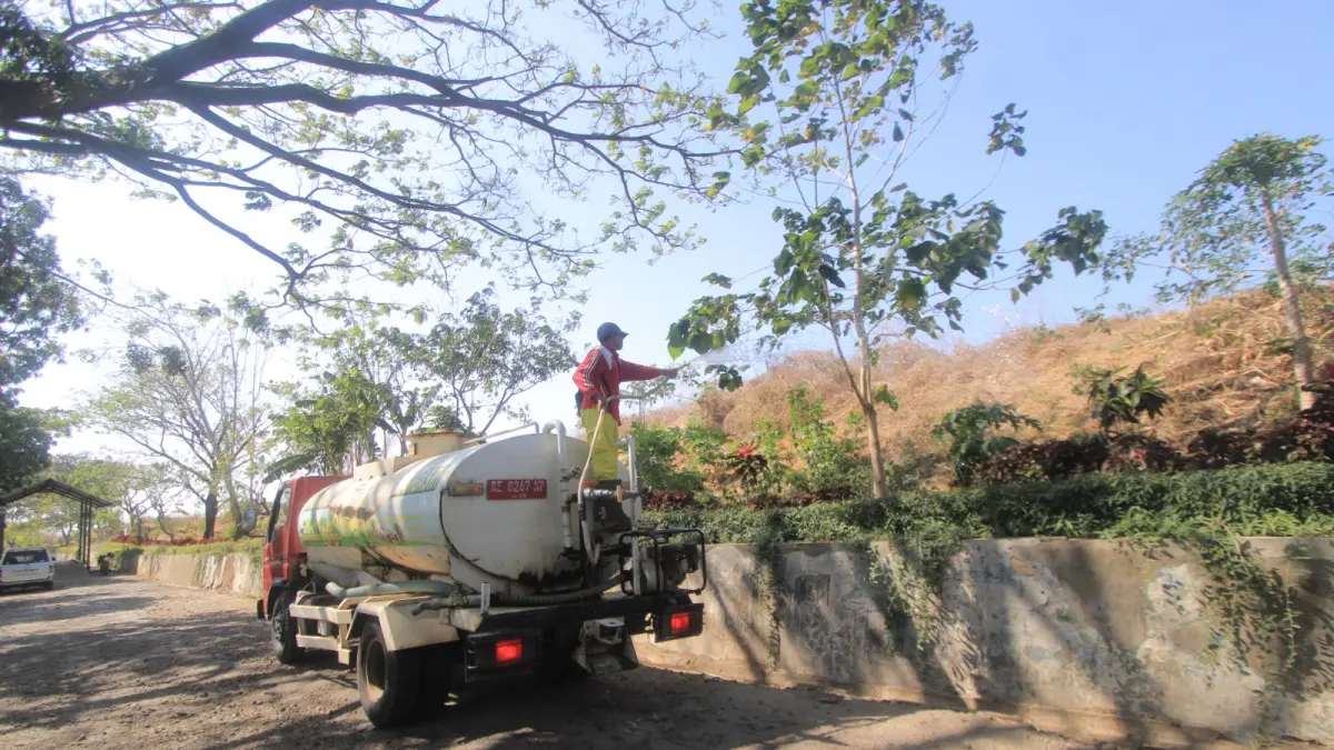 Petugas DLHP Magetan menyiram tumpukan sampah di TPA Milangasri untuk mencegah munculnya titik api saat kemarau. SUGENG DWI N/RADAR MAGETAN