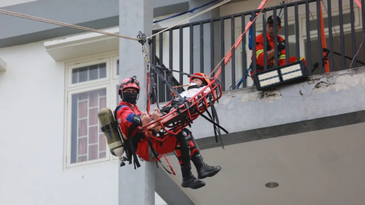 Petugas BPBD Kota Madiun mengevakuasi warga dalam simulasi gempa menggunakan teknik vertical rescue di Rusun Hayam Wuruk. BAGAS BIMANTARA/RADAR MADIUN