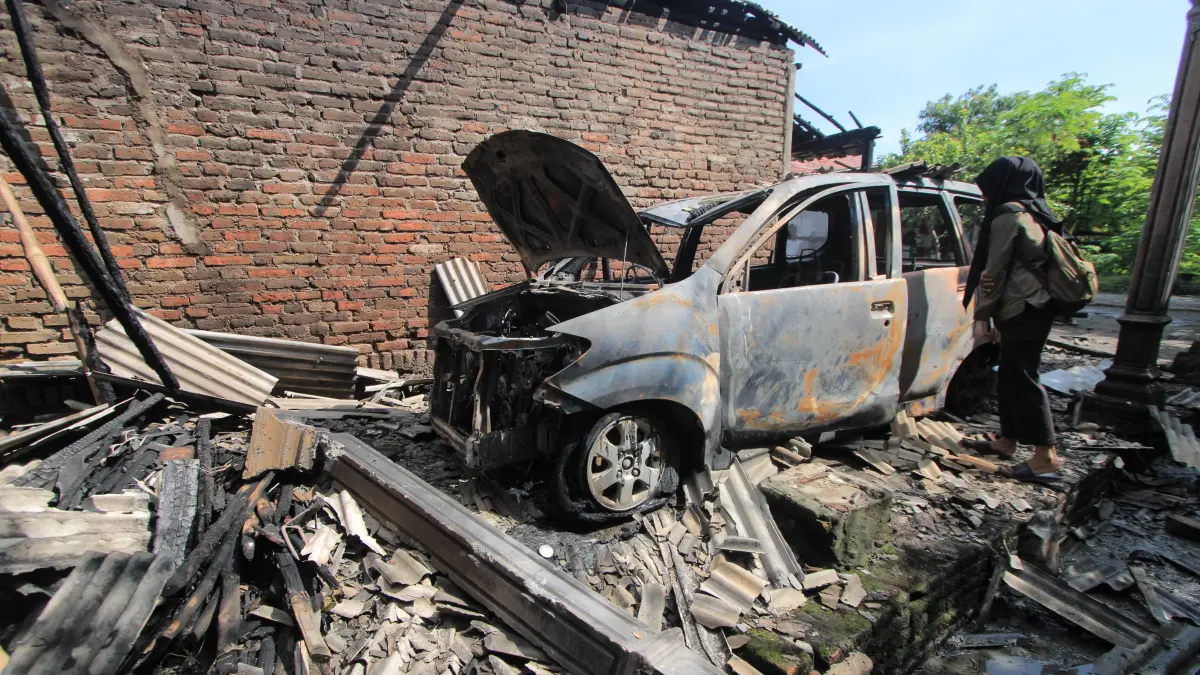 Petugas damkar memadamkan mobil Avanza yang terbakar di garasi rumah warga di Desa Sumberejo, Maospati. AJI PUTRA/RADAR MAGETAN