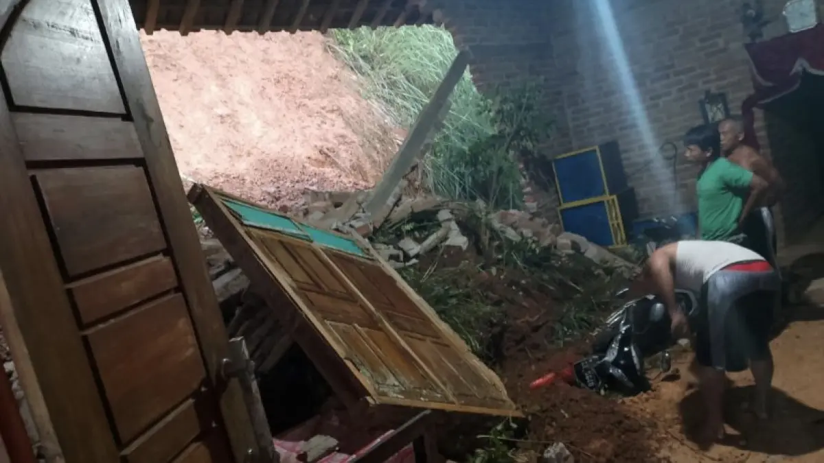 EVAKUASI LONGSOR: Petugas bersama warga membersihkan material tanah yang menghantam rumah di Desa Petungsinarang, Bandar, Pacitan, Kamis (30/4). Empat rumah rusak tanpa korban jiwa.