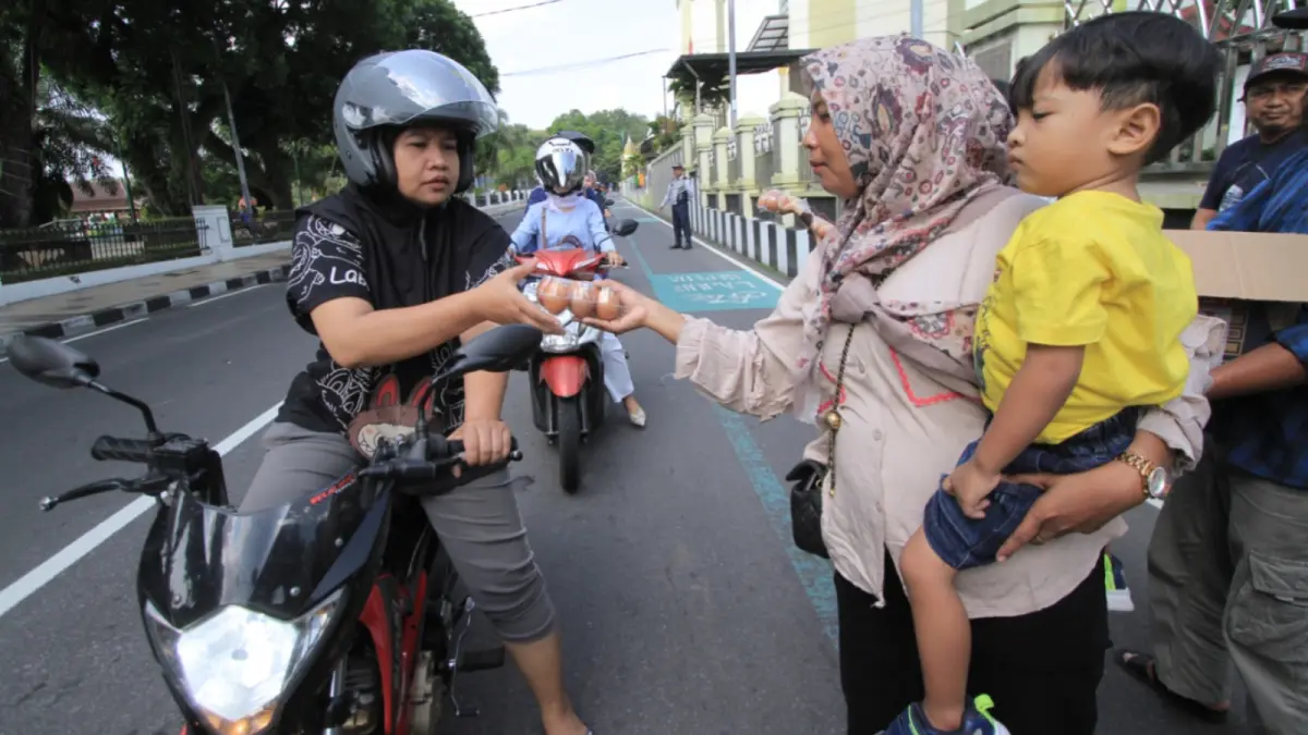 Pengendara menerima paket telur gratis dari peternak ayam petelur saat aksi protes harga telur di Magetan, kemarin (6/5). AJI PUTRA/JAWA POS RADAR MAGETAN