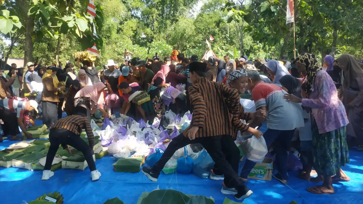 REBUTAN GUNUNGAN: Warga berebut gunungan usai doa bersama di makam Gupitosari. (SATRIO JATI/RADAR MADIUN)