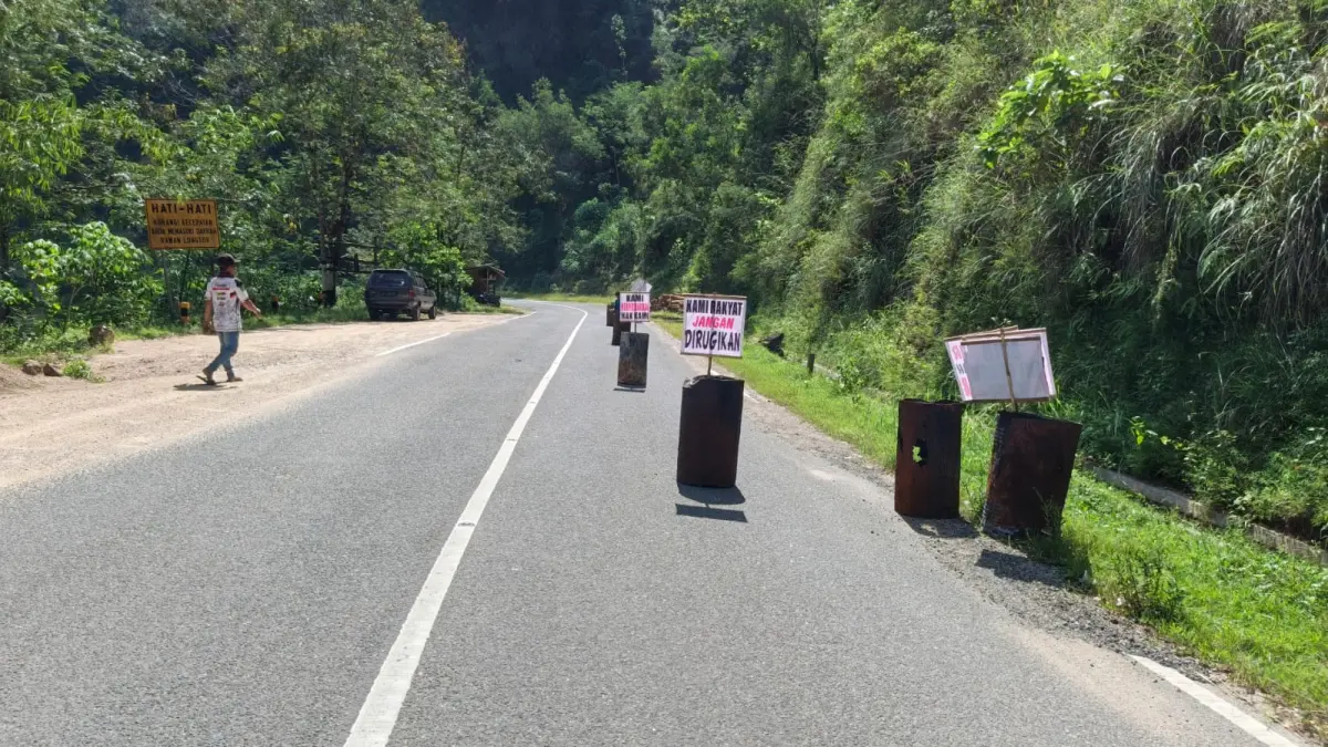 AKSI PROTES: Warga Desa Ngreco dan Kemuning memasang drum serta spanduk di jalur Pacitan–Ponorogo sebagai protes ganti rugi proyek pelebaran jalan yang belum tuntas. NUR CAHYONO/JAWA POS RADAR PACITAN