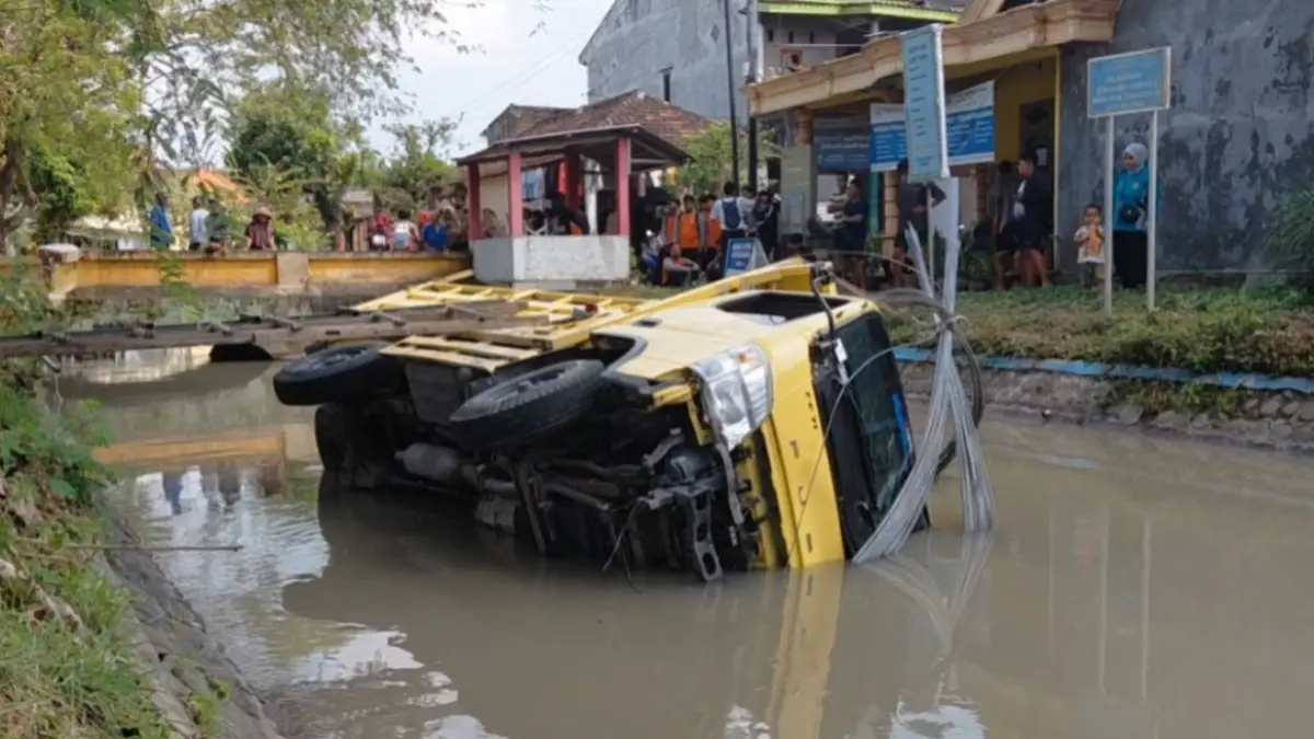 Truk bermuatan semen dan besi tercebur ke sungai di depan SMAN 1 Barat, Kamis (21/5). Sopir diduga panik menghindari sepeda motor. AJI PUTRA/JAWA POS RADAR MAGETAN