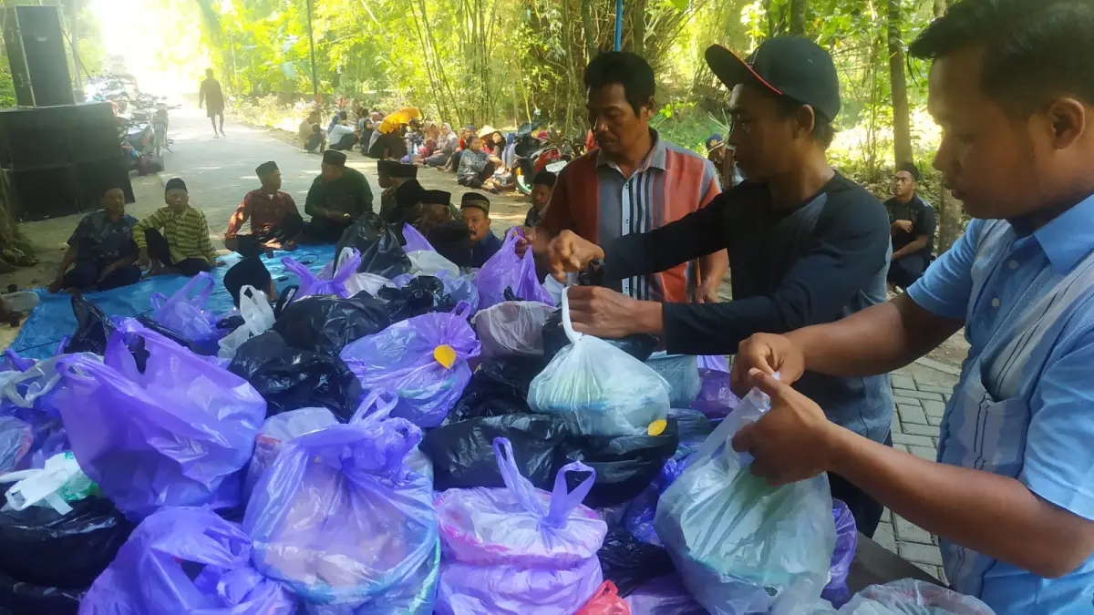 DARI WARGA UNTUK WARGA: Warga berbagi berkat makanan/ambengan usai prosesi doa bersama di Punden Capang sebelum pagelaran Wayang Tengul. (SATRIO JATI/RADAR MADIUN)