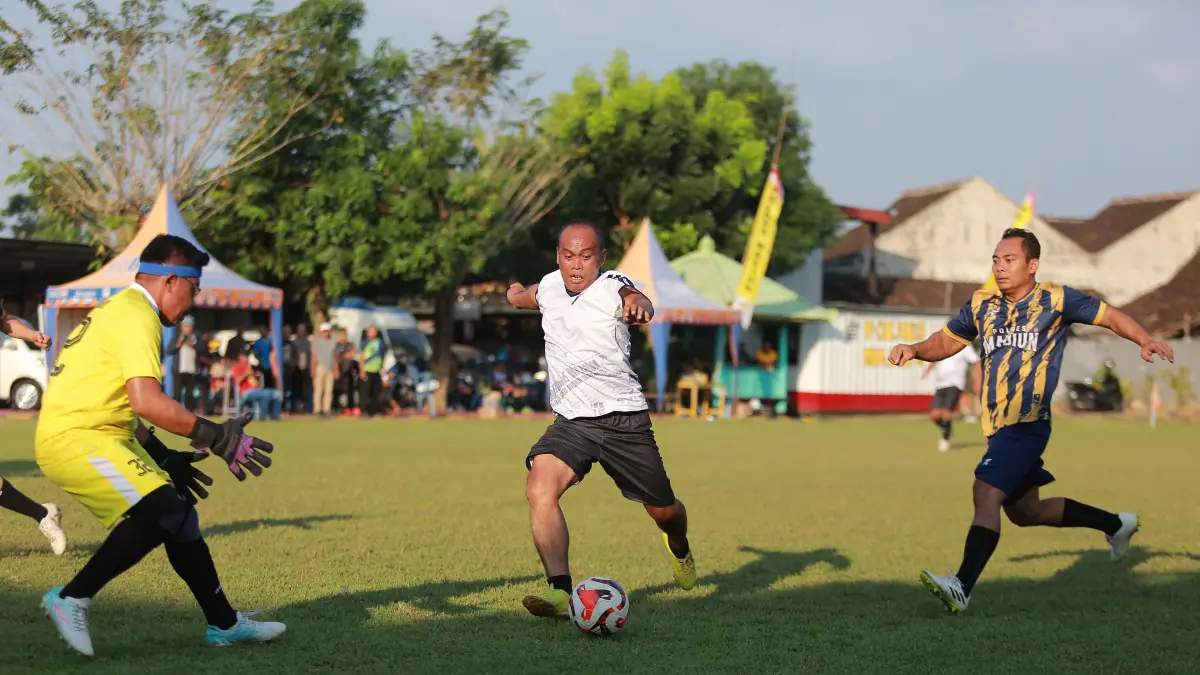 IMBANG DAN LOLOS: Striker Sparta Pena FC Ockta Prana berduel dengan pemain Polres Madiun B dalam laga terakhir Grup D Kapolres Madiun Cup 2026 di Lapangan Tri Brata, Rabu (10/6). LODITYA FERNANDES/RADAR MADIUN