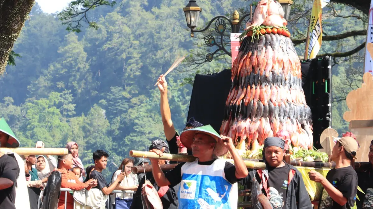 Tumpeng nila setinggi tiga meter hasil karya petani tambak Ngebel diarak mengelilingi Telaga Ngebel sebelum menjadi rebutan warga dalam rangkaian Larung Sesaji Grebeg Suro 2026. SUGENG DWI N/RADAR PONOROGO