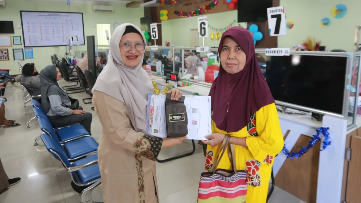 HADIAH HARI JADI: Warga yang mengurus dokumen kependudukan di kantor Dispendukcapil Kota Madiun mendapatkan suvenir berupa mug sebagai bentuk apresiasi pada peringatan Hari Jadi ke-108 Kota Madiun. BAGAS BIMANTARA/RADAR MADIUN