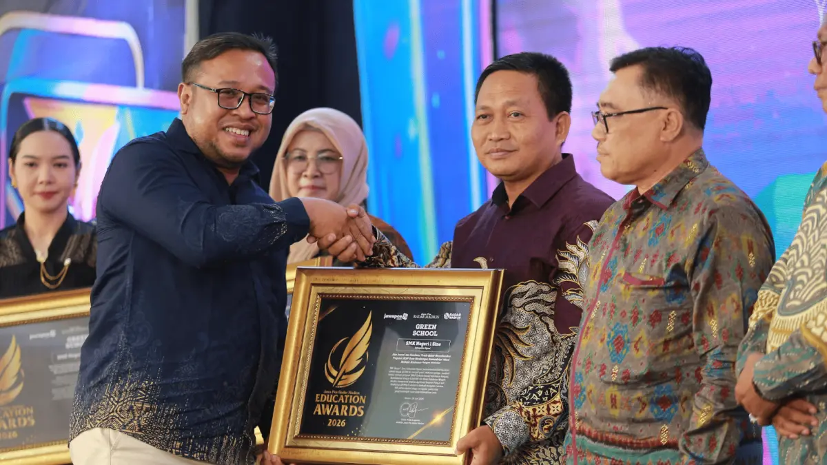 Direktur Jawa Pos Radar Madiun Ockta Prana Lagawira menyerahkan penghargaan Green School kepada Kepala SMKN 1 Sine Agus Budiyono dalam ajang Radar Madiun Education Awards 2026, Minggu (28/6). (BAGAS BIMANTARA/RADAR MADIUN)