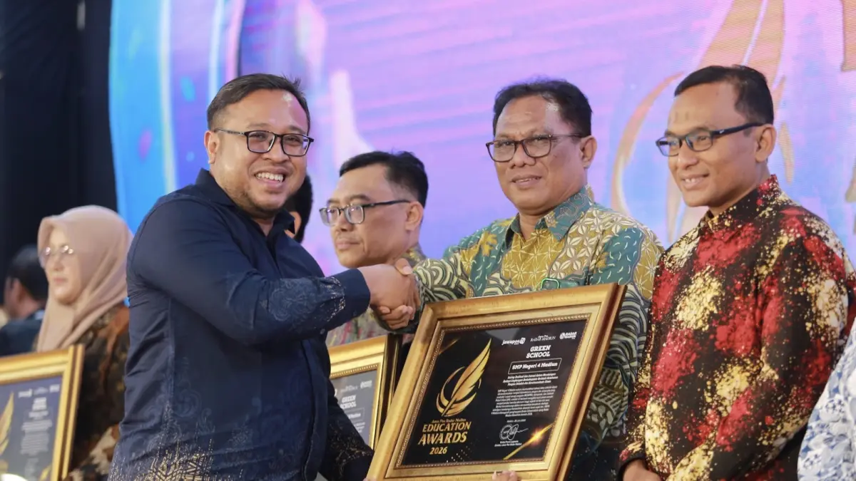 Direktur Jawa Pos Radar Madiun Ockta Prana Lagawira menyerahkan penghargaan Green School kepada Kepala SMPN 4 Madiun Daru Wigyantoro dalam ajang Radar Madiun Education Awards 2026, Minggu (28/6). (BAGAS BIMANTARA/RADAR MADIUN)