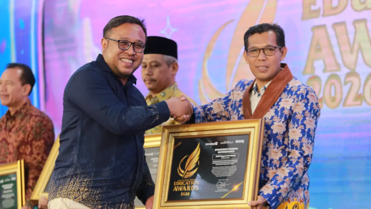 Direktur Jawa Pos Radar Madiun Ockta Prana Lagawira menyerahkan penghargaan Strategic School Government kepada Kepala SMKN 1 Donorojo Achmad Syaifudin dalam ajang Radar Madiun Education Awards 2026, Minggu (28/6). (BAGAS BIMANTARA/RADAR MADIUN) 
