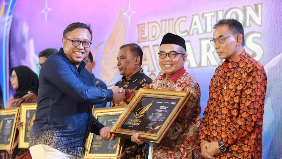 Direktur Jawa Pos Radar Madiun Ockta Prana Lagawira menyerahkan penghargaan Visionary Leader kepada Kepala MTsN 5 Magetan Suwoko dalam ajang Radar Madiun Education Awards 2026, Minggu (28/6). (BAGAS BIMANTARA/RADAR MADIUN)